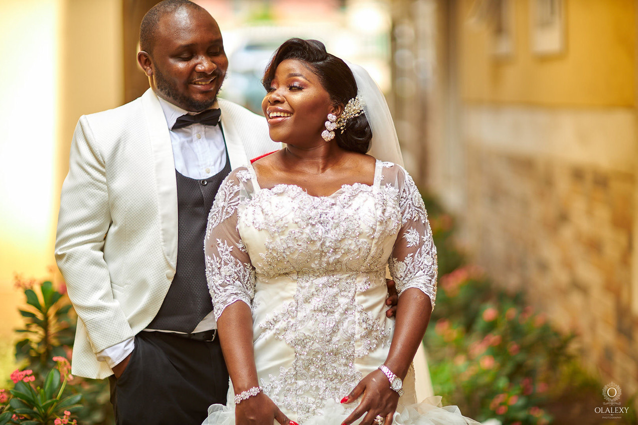 Bride in a flowing couture wedding gown standing in soft light
